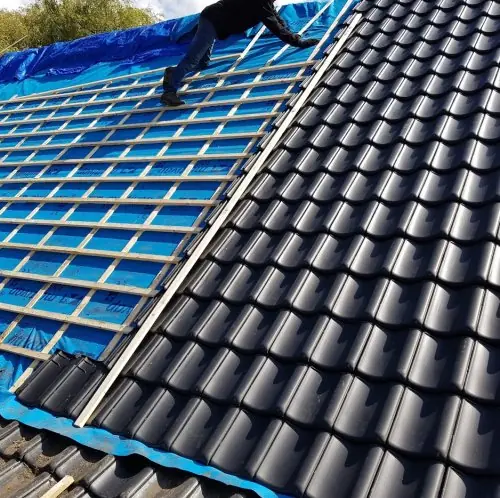 Nieuwe dakpannen worden gelegd op nieuwe panlatten